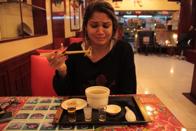 o que fazer em Taiwan Uma mulher tomando sopa de cobra em um restaurante de Taiwan. Há também três shots diferentes em cima da mesa. Ela faz uma careta enquanto olha para o seu hashi.