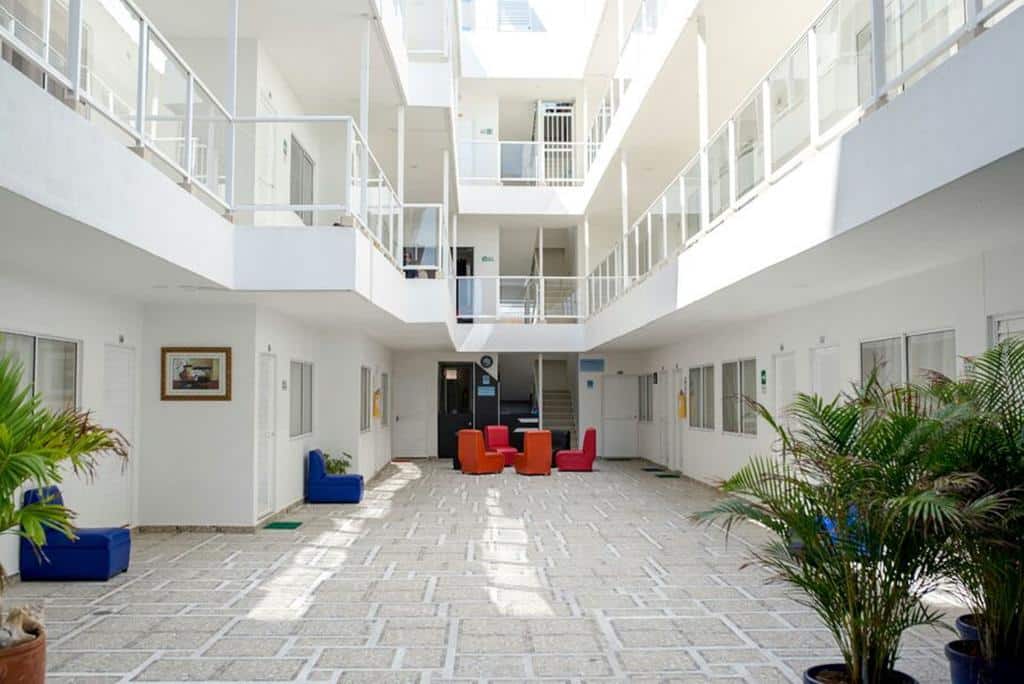 Área comum principal do hotel Caribbean Island, com paredes brancas e poltronas coloridas.