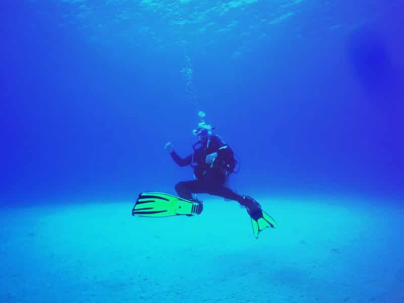 Instrutor de mergulho embaixo d'água, em área de oceano aberto do mar caribenho.