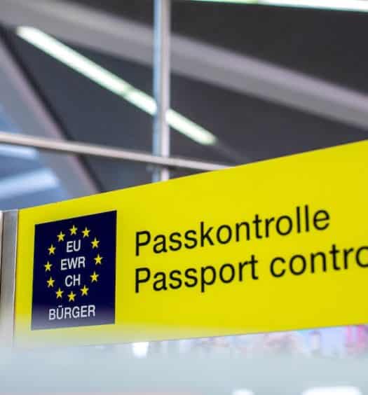 Placa de "passport control" num aeroporto europeu, com fundo amarelo e letras em tom escuro, para ilustrar o post sobre documentos para entrar na Europa