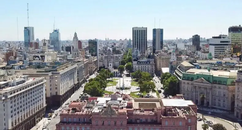 Vista aérea de uma paisagem urbana com um grande edifício governamental rosa e estruturas históricas e arranha-céus ao redor.