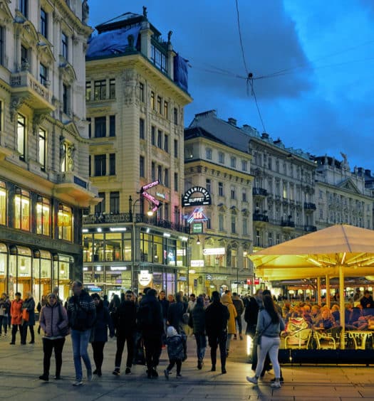 Vista de rua em Viena, com pessoas caminhando em volta de prédios da cidade, em post com dicas de onde ficar em Viena. Foto de Pedro Szekely