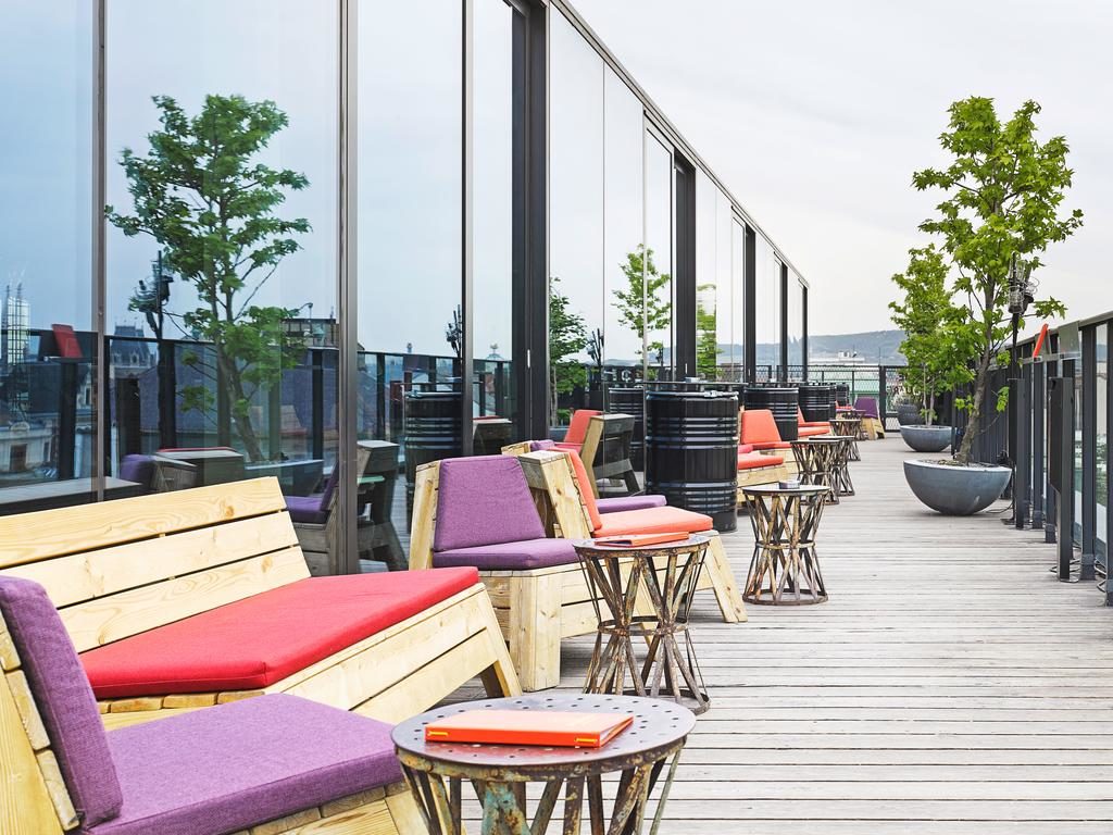 Foto de terraço do hotel, com bancos/cadeiras estofados com almofadas vermelhas ou roxas.