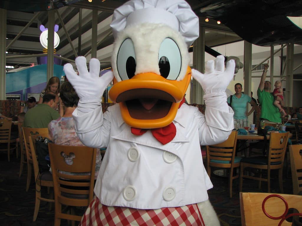 Pato Donald com as mãos pra cima em foto dentro do restaurante Chef's Mickey, no Disney Magic Kingdom