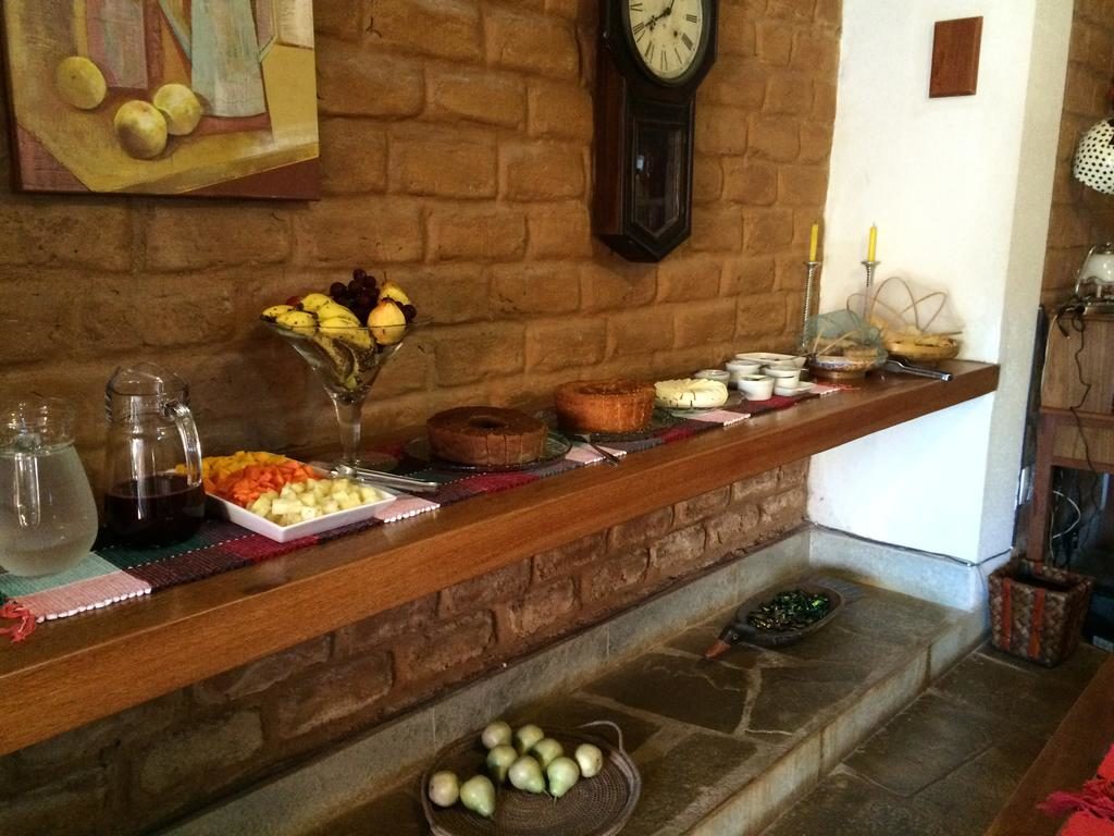 Café da manhã da com bolo, sucos, frutas e pães na Pousada Pouso 22, área de alimentação da pousada.