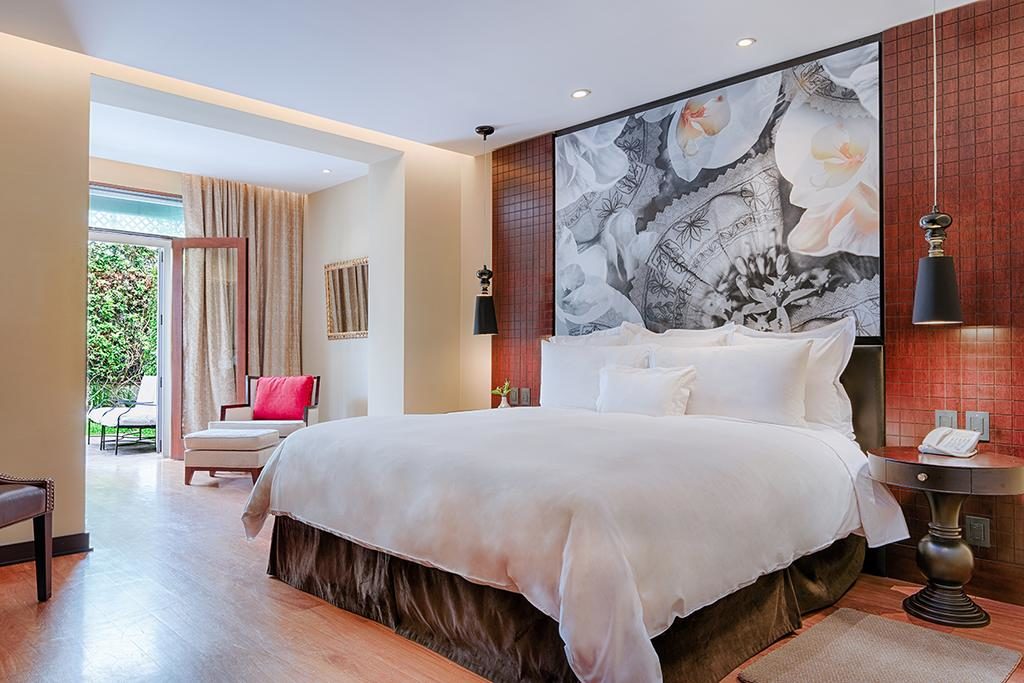 Foto de uma das suítes do Country Club Lima Hotel, com cama, poltronas, luzes, mesinha e boa decoração.