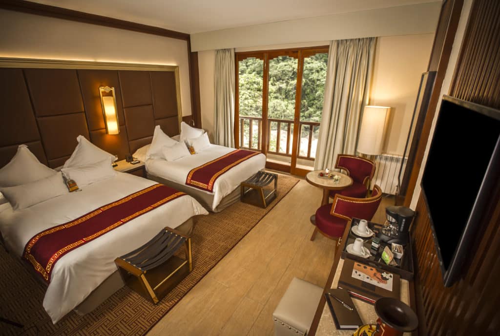 Foto de quarto do hotel Sumaq, com duas camas de casal, decoração inspirada nos incas, TV plana e vista para o rio da varanda,