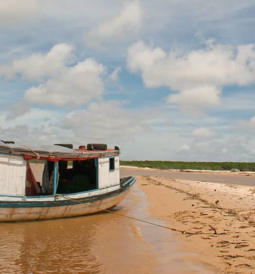 Paisagem de dunas e barco na água no Delta do Parnaíba, encontro do rio com o mar no nordeste brasileiro