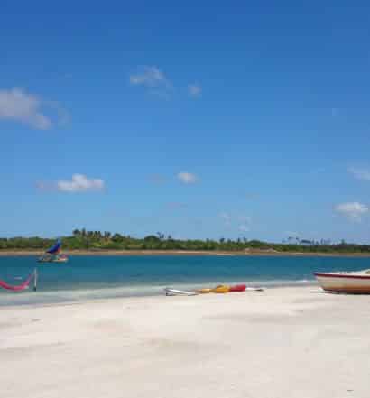 Jericoacoara, no Ceará, com praia de areia clara e mar azul turquesa, barco em dia de céu limpo e sol