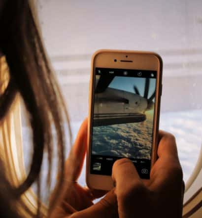 mulher usando chip de celular para viagem internacional para fotografar a janela do avião