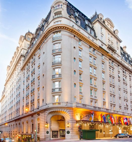 Foto do Alvear Palace Hotel, uma das recomendações de melhores hotéis na Recoleta em Buenos Aires. É um prédio bege de 9 andares com bandeiras de diversos países na entrada.