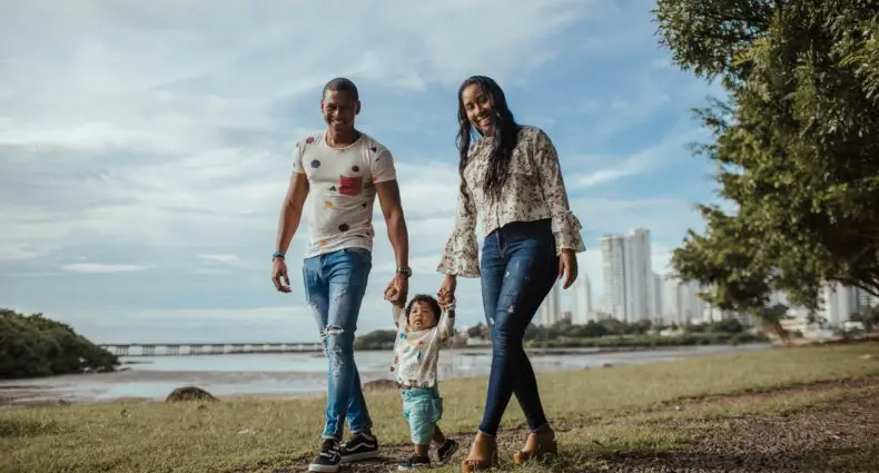 pai e mae caminhando junto com seu filho pequeno