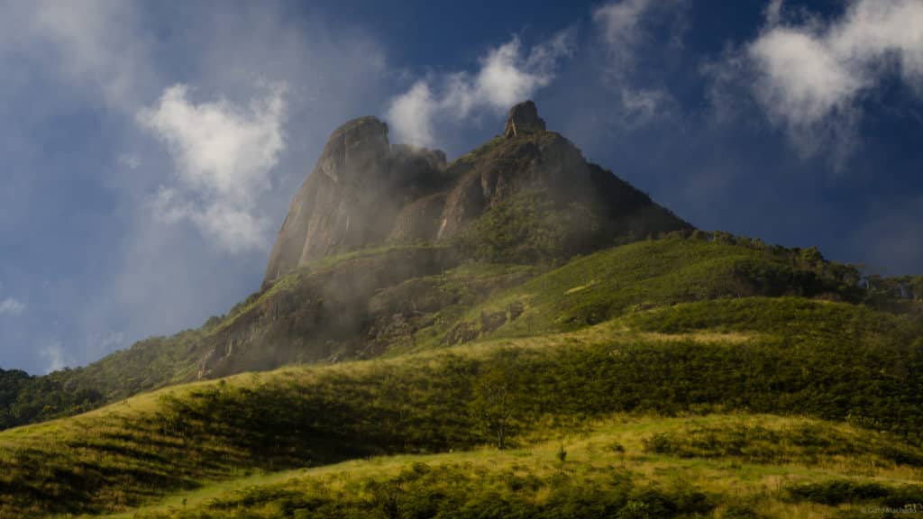 Imagem da Pedra Selada em Visconde de Mauá que mostra o pico da pedra ao fundo e em volta bastante vegetação verde durante o dia. Imagem ilustrando post O que fazer em Visconde de Mauá.