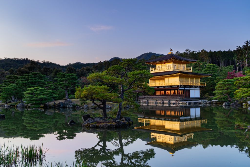 Castelo japonês em lago com floresta ao fundo, na cidade de Kyoto, no Japão
