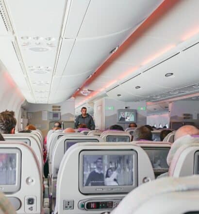 Interior de um avião, com telas em casa banco, ilustrando a capa do post sobre dicas para curtir uma viagem de avião
