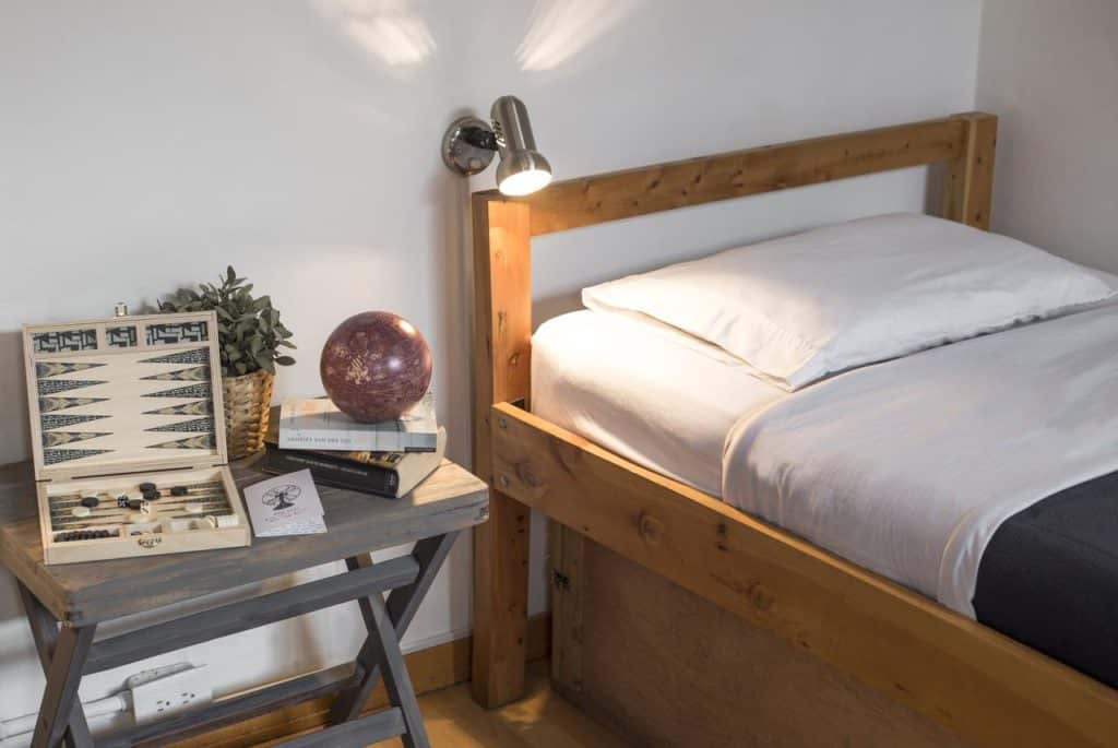 Cama e mesinha de cabeceira no Explora Hostels