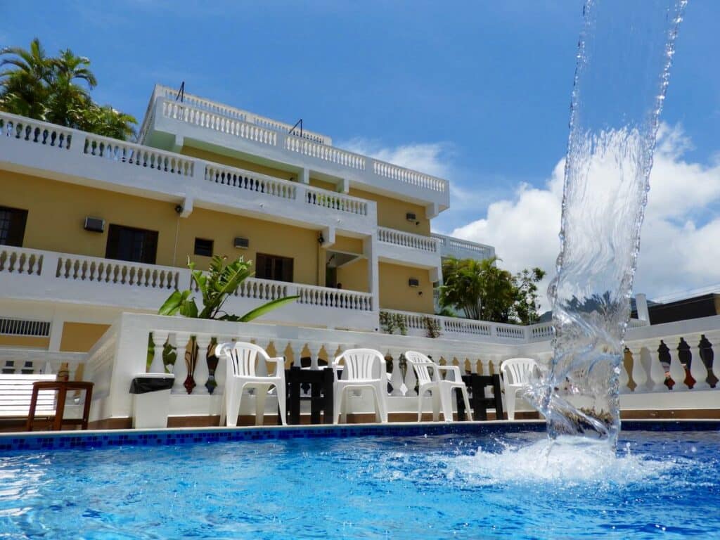 Área externa com piscina do Hotel Parque Atlântico, com cascata de água e cadeiras nos arredores