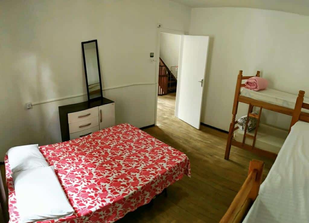 Quarto família do Hostel Roa do Vale, de 35 m², com uma cama de casal, duas beliches e uma escrivaninha preta e branca com espelho