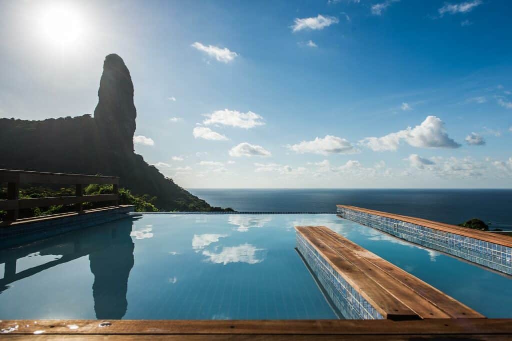 Água da piscina de borda infinita, com vista para o Morro do Pico, refletindo o céu, na Pousada Filó, em Fernando de Noronha