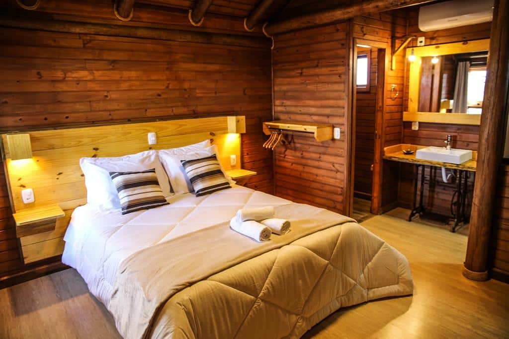 vista interna do quarto da Pousada Morada da Serra com uma cama de casal, um ar-condicionado, um banheiro e uma pia externa