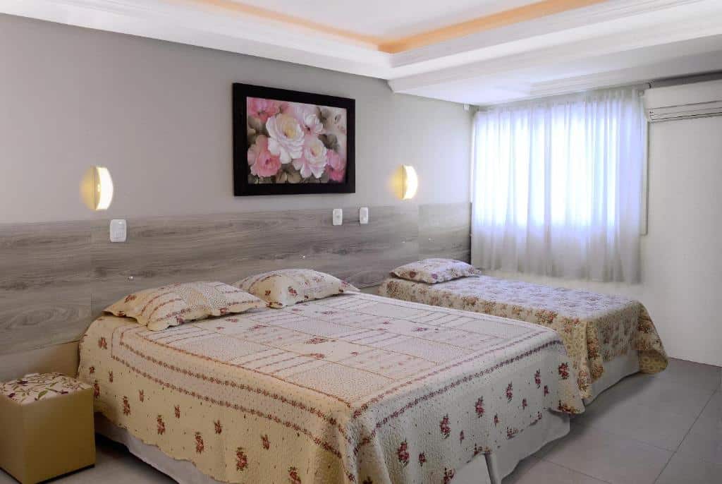 Quarto para família na Pousada Florenza em Bento Gonçalves, com cama de casal, cama de solteiro, cortina voil na janela e ar-condicionado