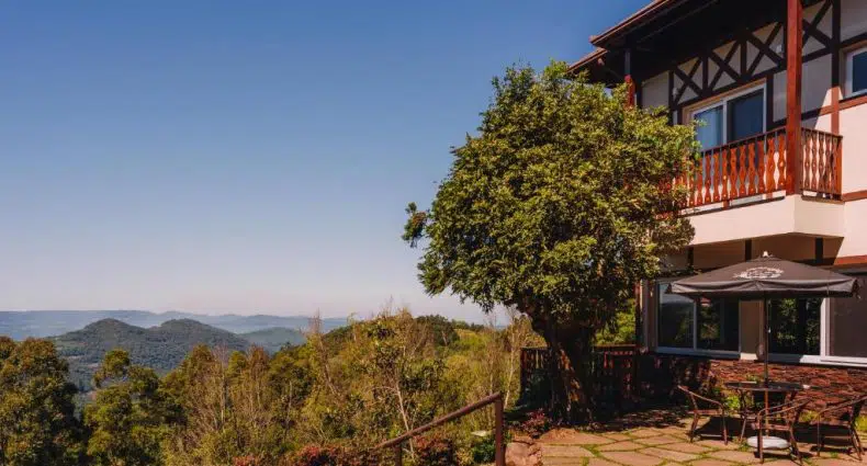 Hotel Jardins da Colina na Serra Gaúcha, com parte da estrutura com varanda em primeiro plano, e montanhas ao fundo