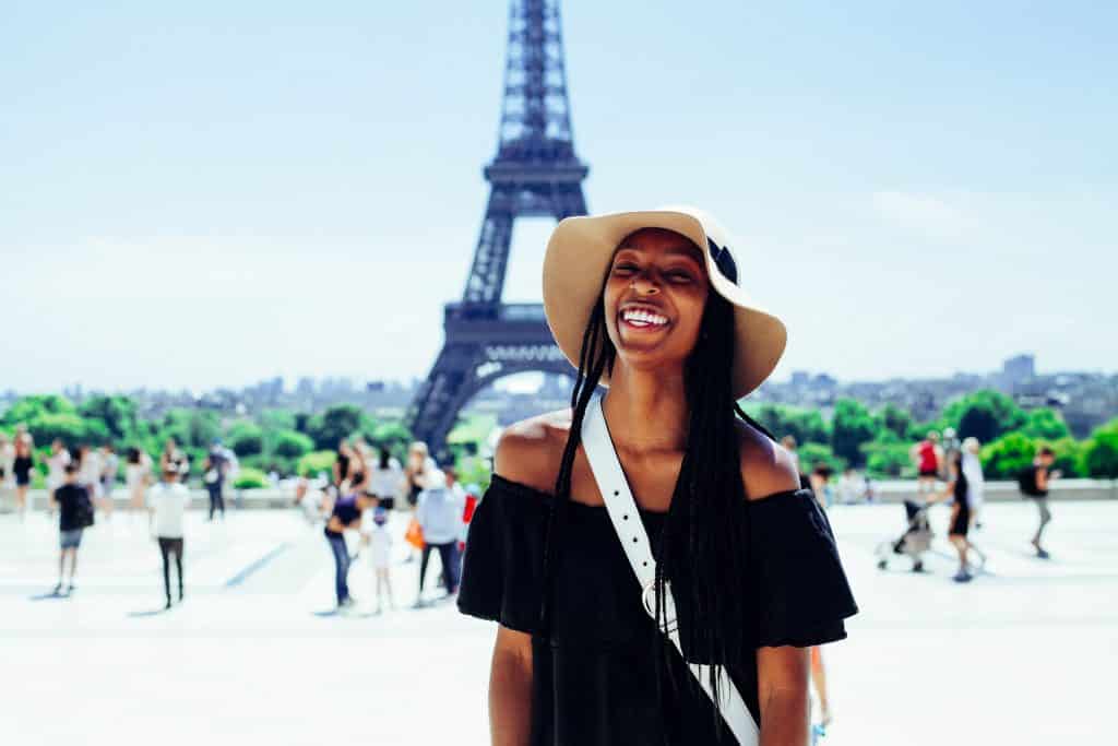Mulher sorrindo em frente à Torre Eiffel, ilustrando post de cupom de desconto Seguros Promo