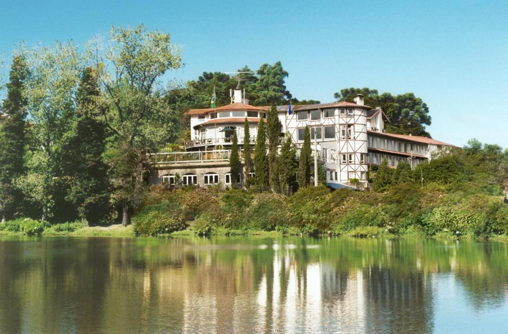 vista frontal do Hotel Estalagem St. Hubertus em frente ao lago negro em Gramado e rodeado pela vegetação natural do município.