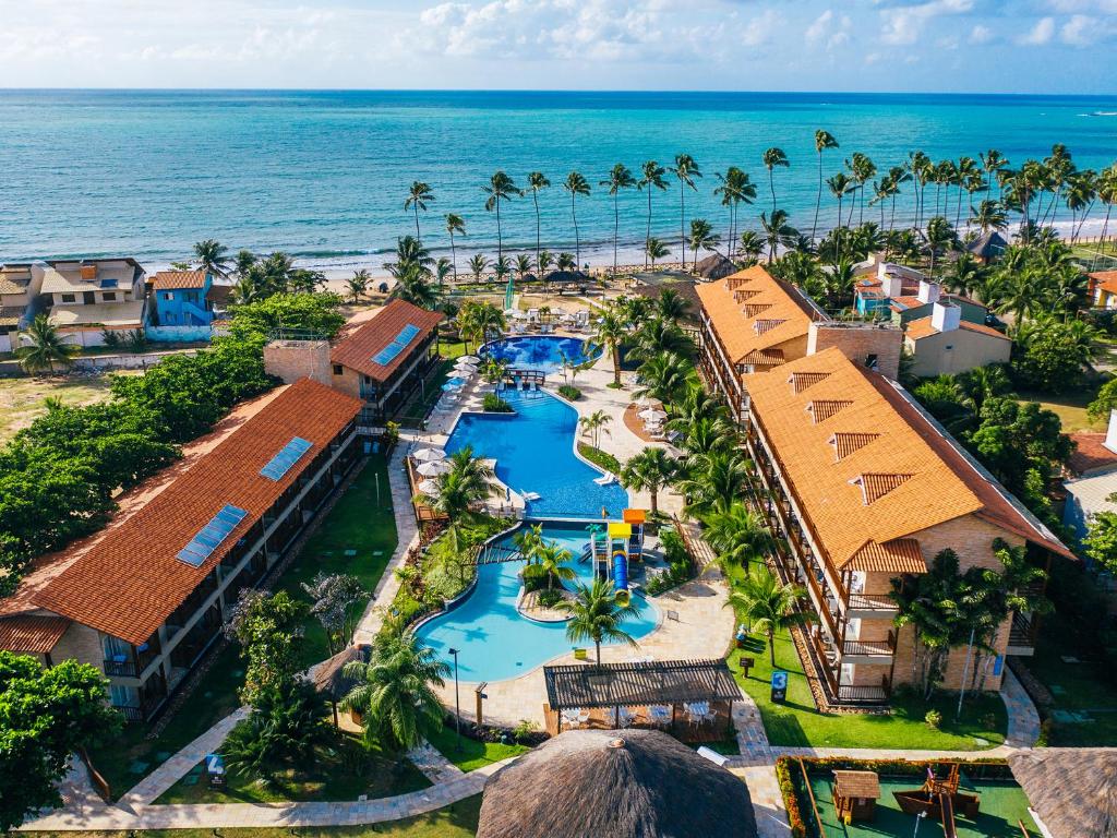 vista aérea do Salinas Maceio All Inclusive Resort em Alagoas com o mar ao fundo pontilhado por coqueiros e uma ampla piscina entre as casas do resort