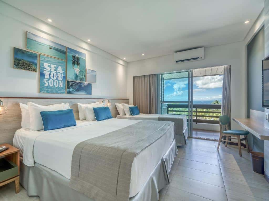 suíte no Japaratinga Lounge Resort com uma cama de casal e uma cama de solteiro, uma varanda com vista para o mar e uma mesa para trabalho