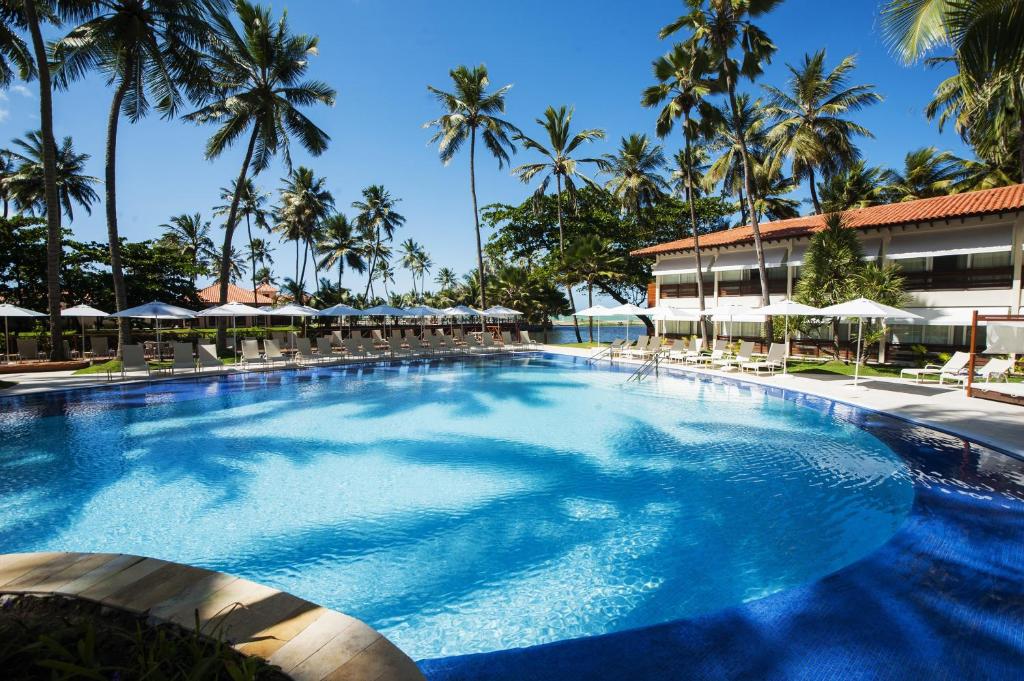 piscina rodeada de coqueiros altos do Jatiúca Hotel & Resort em Maceió
