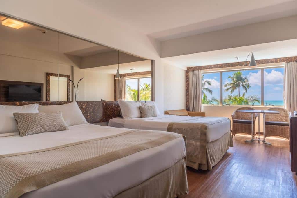 suíte do Ritz Lagoa da Anta Hotel & SPA com duas camas de casal e uma ampla janela com vista para o mar