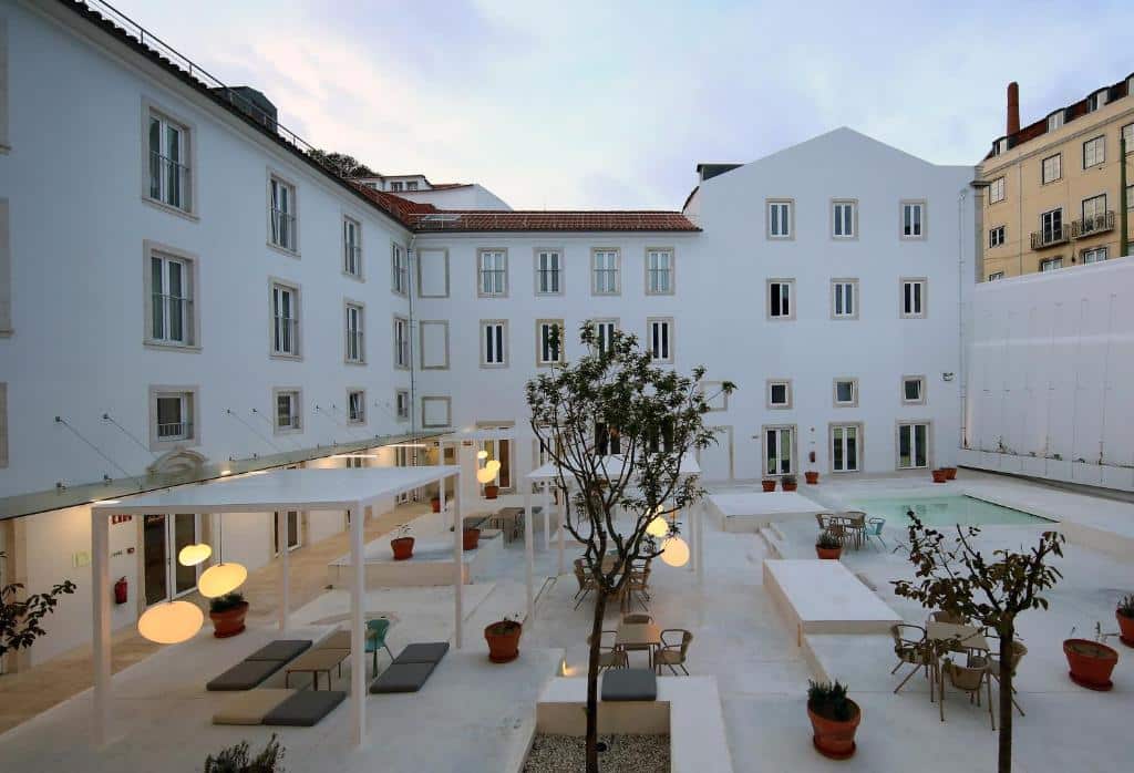 Parte do pátio interno do Hotel Convento do Salvados, um dos hotéis em Lisboa, onde há uma piscina e áreas cobertas com mesa e cadeiras