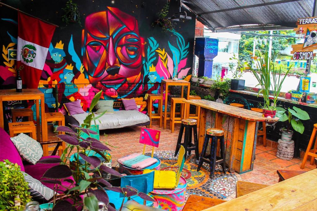 lounge compartilhado do Supertramp Hostel Machupicchu com muita arte urbana nas paredes, mesas e cadeiras de madeira dispostas pelo espaço, além de pufes e futons coloridos no chão.