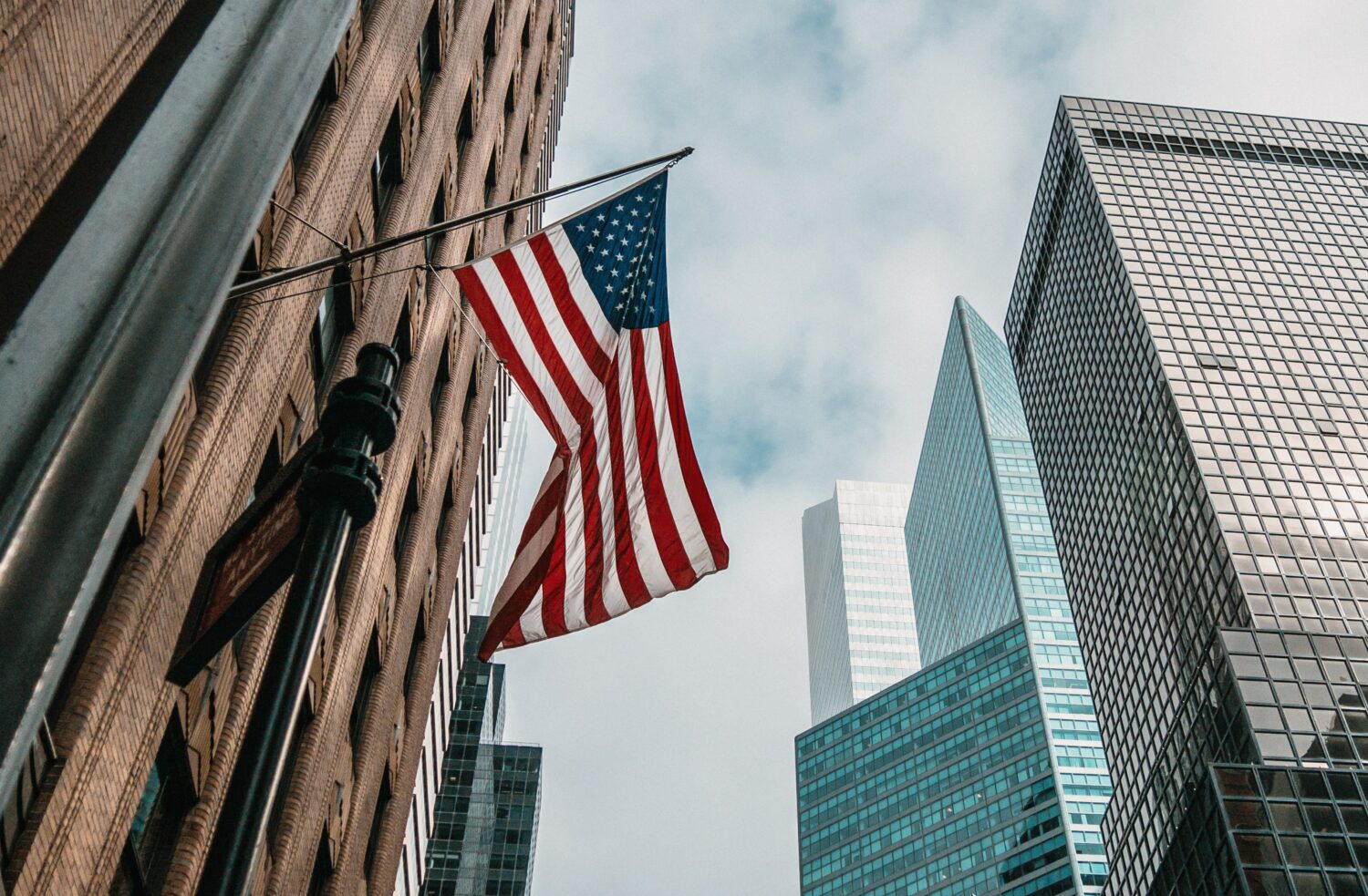 Bandeira dos EUA em prédio de Nova York, ilustrando a capa do post de seguro viagem Estados Unidos - Foto: Nik Shuliahin via Unsplash