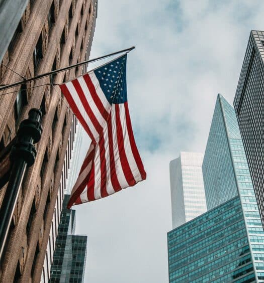 Bandeira dos EUA em prédio de Nova York, ilustrando a capa do post de seguro viagem Estados Unidos - Foto: Nik Shuliahin via Unsplash