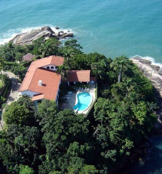 Vista aérea da Casa Genoveva na Praia do Tenório, cercado pelo mar, rochas e vegetação