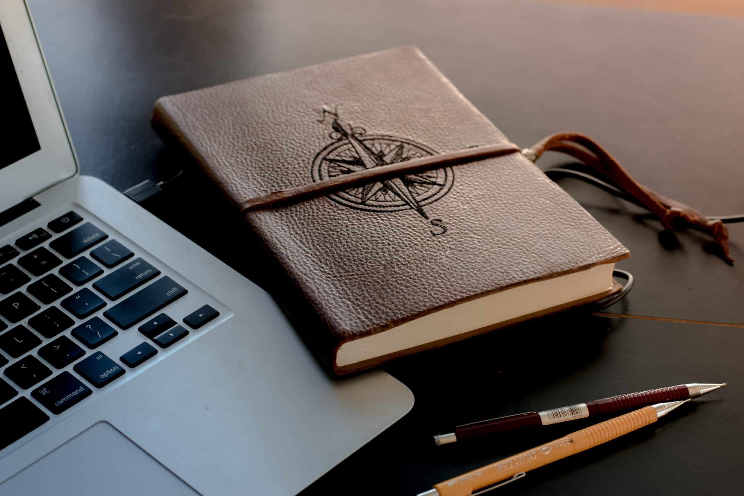 caderno de viagem ao lado de um notebook - foto tirada pelo colton sturgeon via unsplash