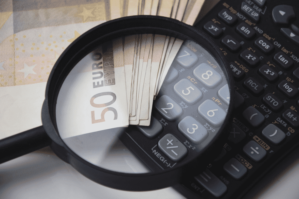 calculadora com lupa e notas de 50 euros representando a cotação de seguro viagem barato