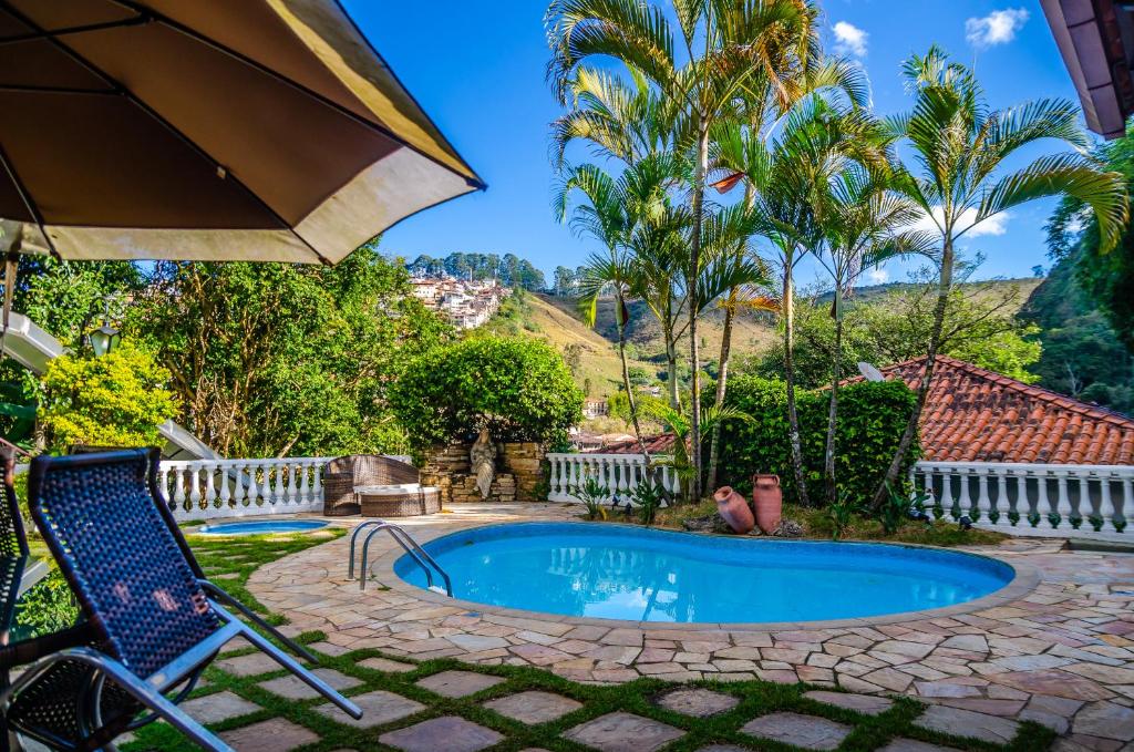 área da piscina com jardim e vista das montanhas na Pousada Arcádia Mineira em Ouro Preto