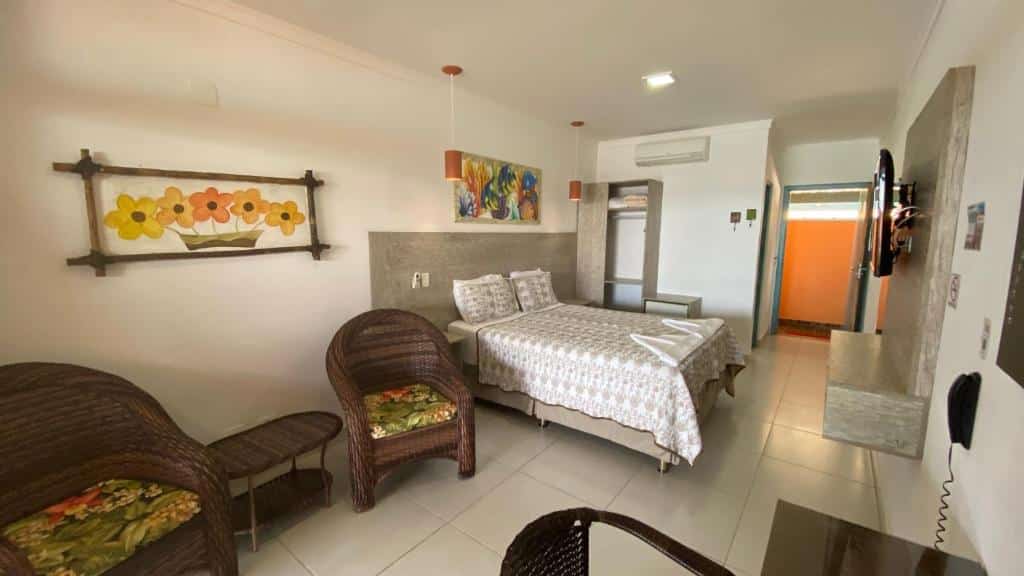 Quarto amplo na Kaliman Pousada, uma das opções de hotéis em Ubatuba, com cama de casal, TV, ar-condicionado e poltronas