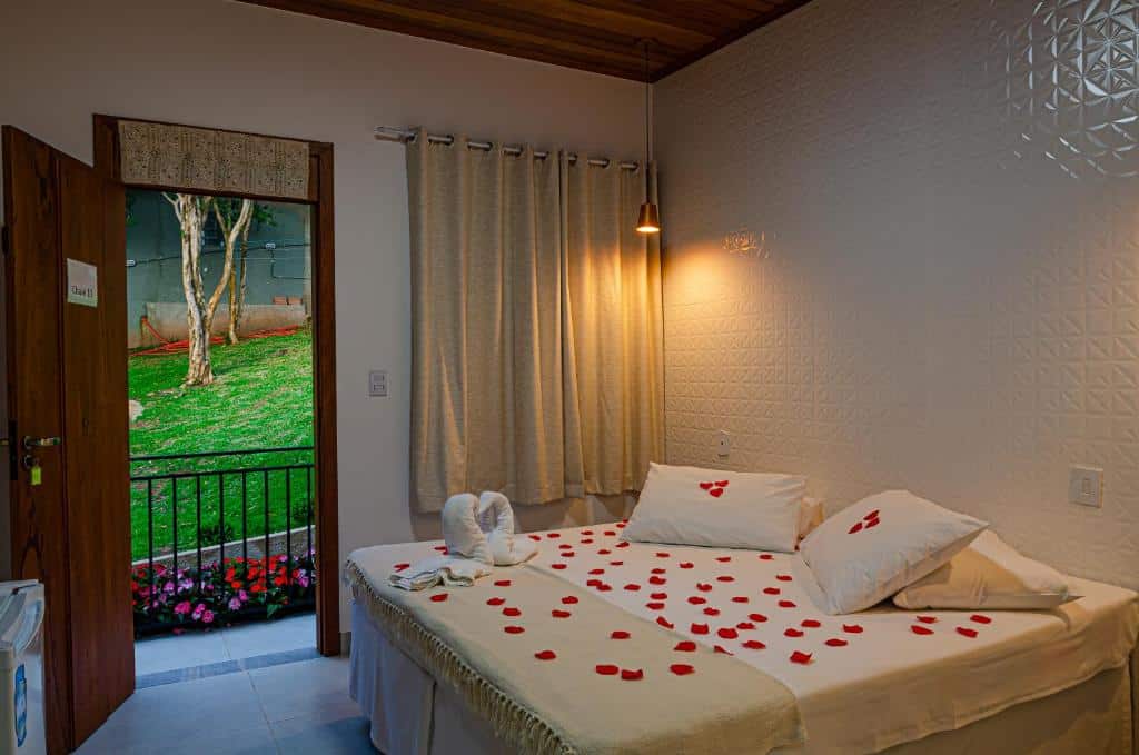cama de casal enfeitada de pétalas vermelhas dentro do quarto da Pousada Vila Catarina