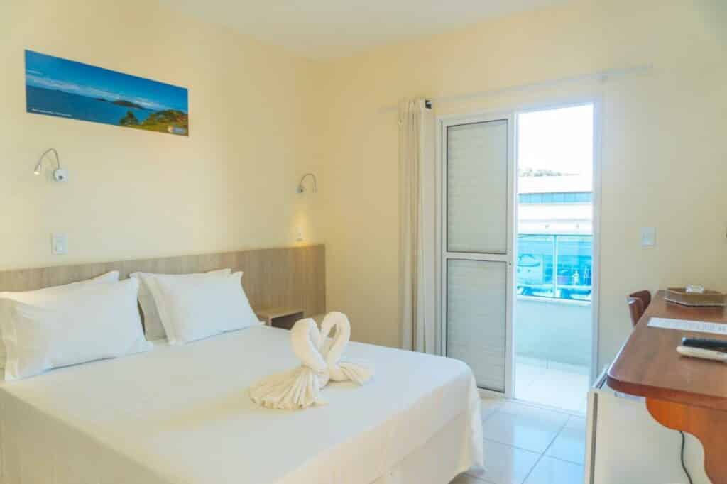 Quarto do Ubatuba Praia Hotel, com cama de casal, varanda e toalhas em formato de cisne