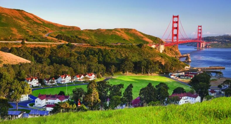 Colinas verdes com vista para prédios brancos e a ponte Golden Gate, a partir do Hotel Cavallo Point, para representar onde ficar em San Francisco.