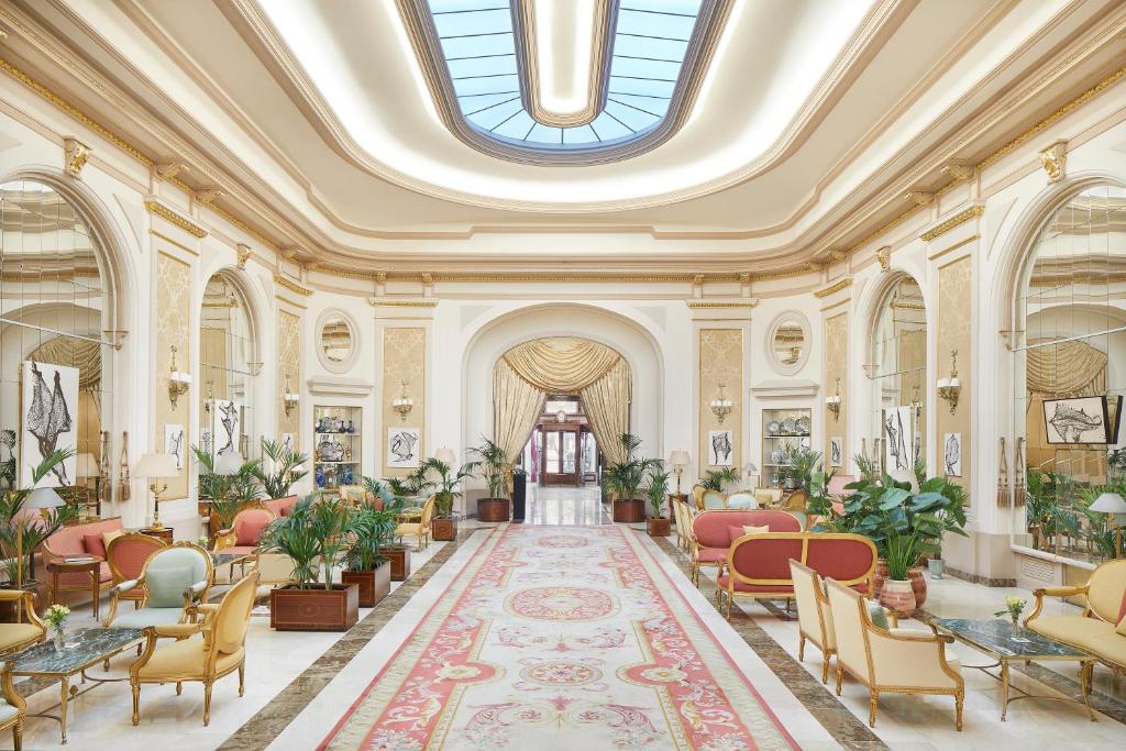 Interior do Hotel El Palace, que imita um castelo moderno com muitos detalhes circulares em dourado e branco. Um tapete decorado, cadeiras de alças estofadas e cortinas douradas exalam riqueza pela sala.