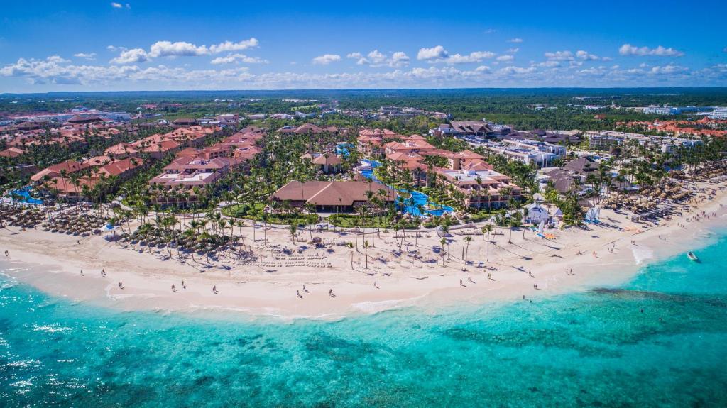 Vista aérea do Majestic Colonial Punta Cana, onde há várias piscinas e prédios numa área repleta de vegetação e acesso à praia.