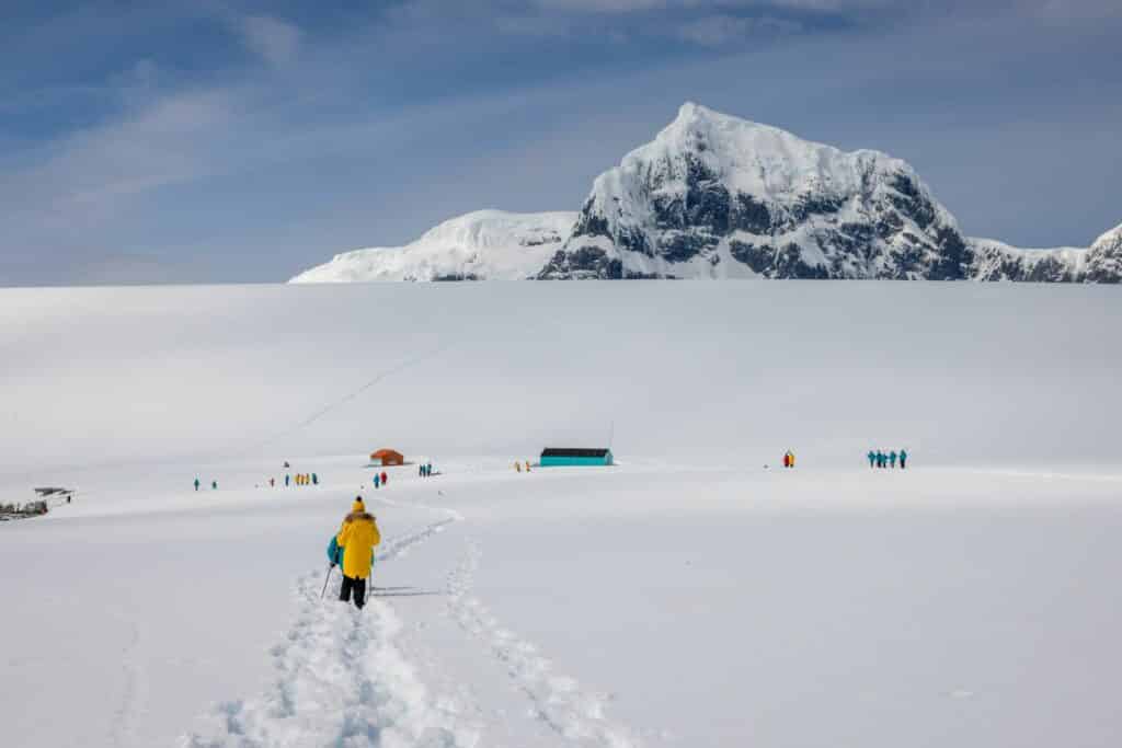 Pessoas caminhando em imensidão de gelo no continente antártico