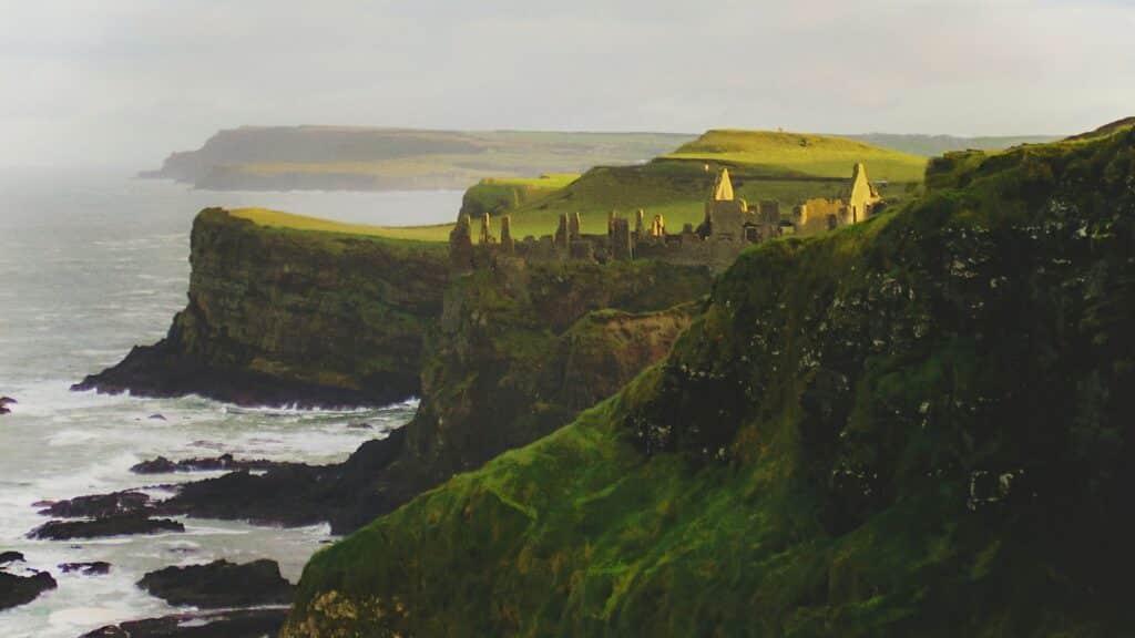 vista da baía com o castelo de dunluce ao fundo da irlanda do norte que pode ser visitada com o seguro viagem reino unido
