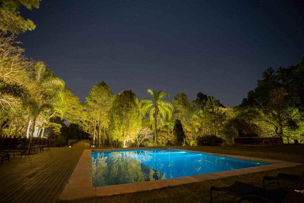 Piscina iluminada e árvores do Canto do Irere durante a noite. Representa hotéis em Atibaia.