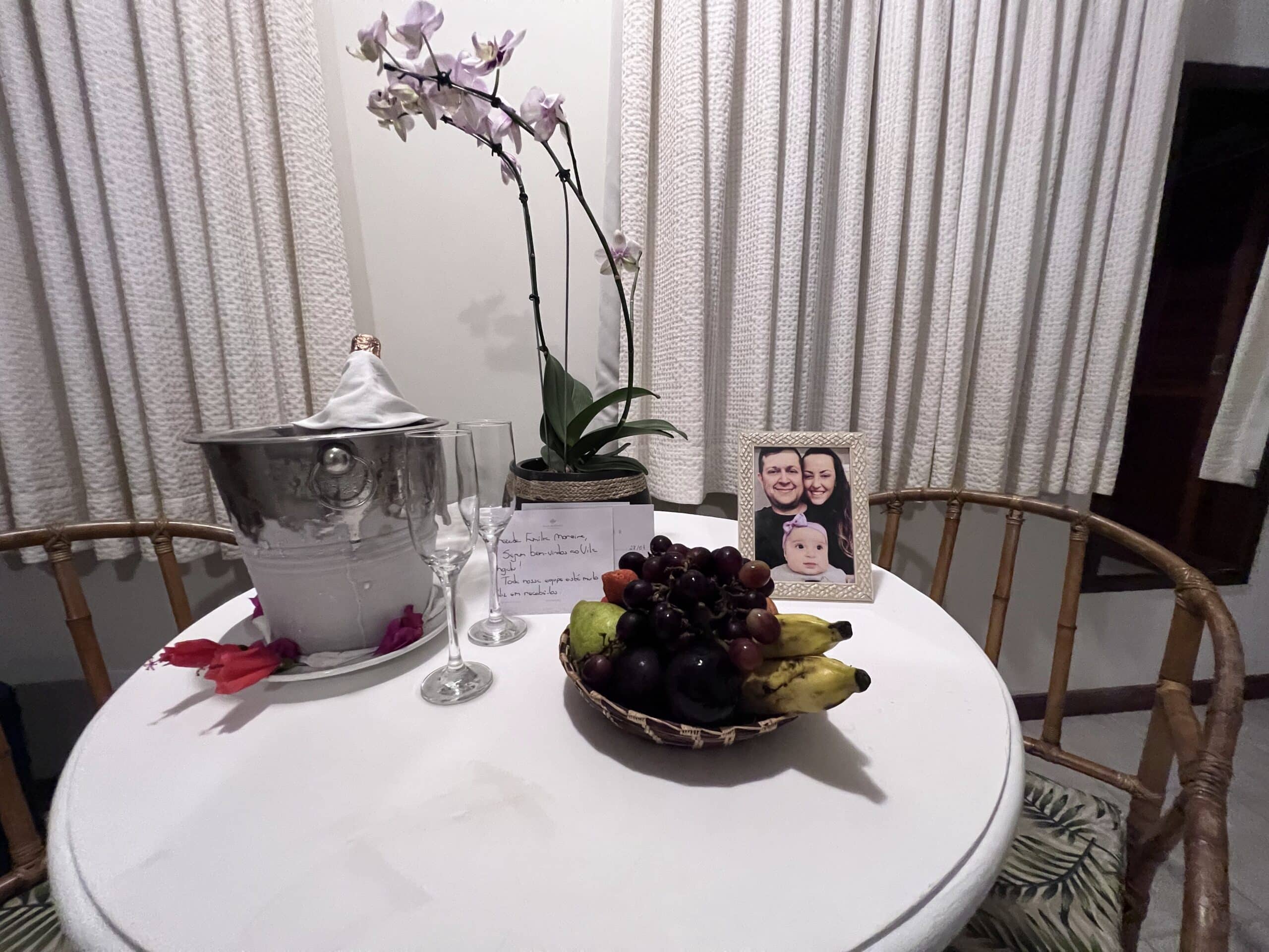 Mimos na chagada ao quarto do Vila Angatu Eco Resort & Spa, com garrafa de champanhe, taças, frutas, cartinha e porta-retrato com foto do Flávio, Ju e Manu